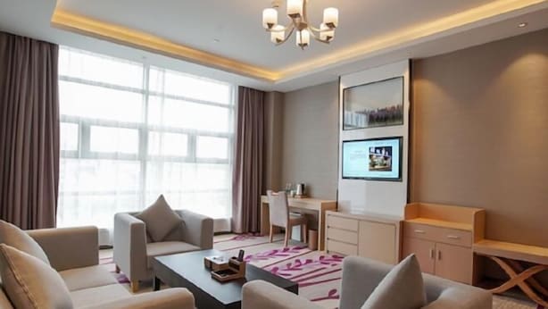 A modern hotel room with a sofa set, a desk, and a large window. - Lavande Hotel (Dongguan)