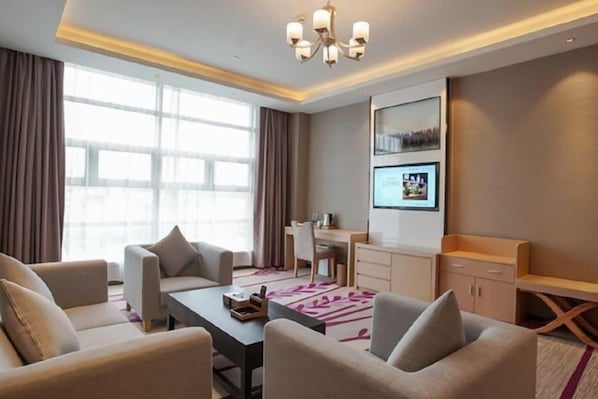 A modern hotel room with a sofa set, a desk, and a large window. - Lavande Hotel (Dongguan)