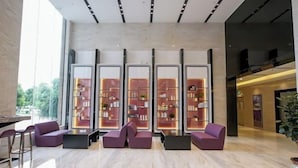 A modern lobby with a marble floor, purple seating, and glass-fronted shelves with various items. - Lavande Hotel (Dongguan Chang'an Fuhu) (Dongguan)
