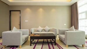 A modern hotel room with a sofa set, a coffee table, and a striped carpet. - Lavande Hotel (Dongguan)