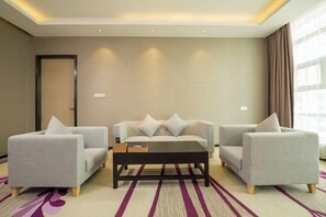 A modern hotel room with a sofa set, a coffee table, and a striped carpet. - Lavande Hotel (Dongguan)