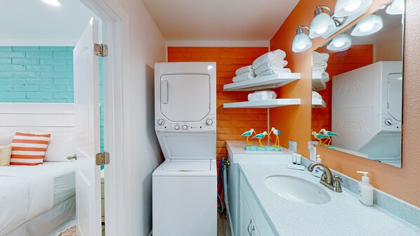 A bathroom with a white sink, a mirror, and a white washing machine. - Ground Floor Condo, Shared Pool, Grills and Boardwalk (Port Aransas)