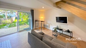 Una sala de estar moderna con un sofá gris, un televisor y una mesita de noche con una lámpara.