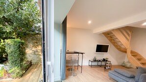Una sala de estar moderna con una escalera de madera, un televisor montado en la pared y una zona de estar acogedora.