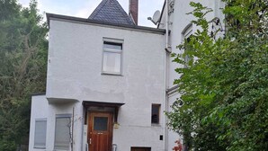 A two-story white building with a wooden front door, a satellite dish, and a chimney. - Apartment at Levinscherpark, 3km from downtown (Göttingen)