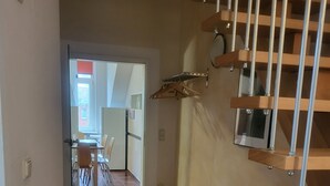 A hallway with a staircase, a dining area in the background, and a white cabinet with a wooden top. - Apartment at Levinscherpark, 3km from downtown (Göttingen)
