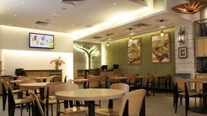 Un ristorante con tavoli e sedie rotonde, un angolo cucina e opere d'arte alle pareti.