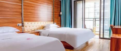 A hotel room with two beds, wooden paneling on the walls, a large window with curtains, and a balcony.