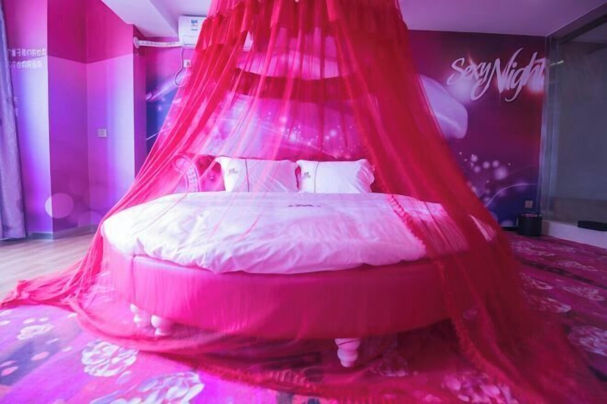 A bed with a red canopy, a white pillow, and a wall with a 'Say Night' sign.