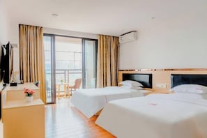 Habitación de hotel con dos camas, un escritorio, una silla y un balcón con cortinas.
