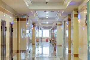 A hotel corridor with doors numbered 1001, a ceiling with recessed lighting, and a reflective floor.