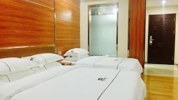 A hotel room with two beds, wooden paneling on the walls, a large mirror, and a door.