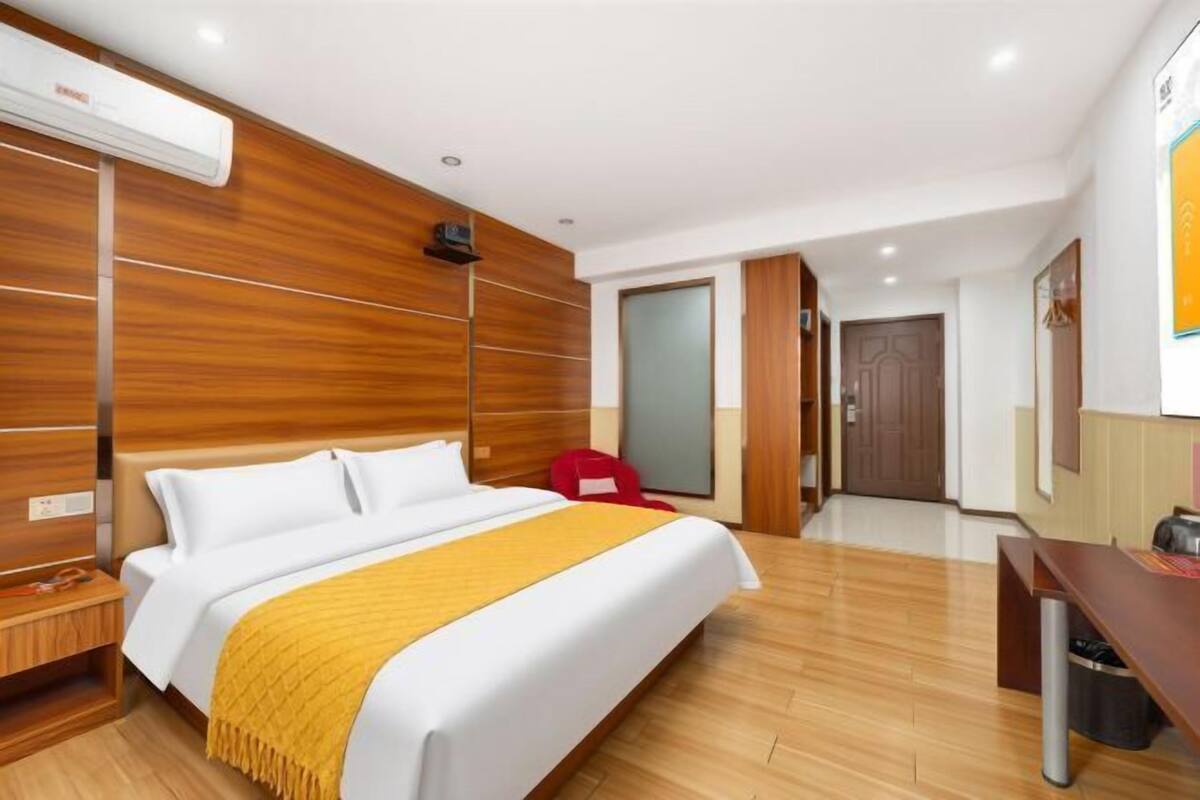 A hotel room with a bed, a desk, a chair, and a wardrobe.