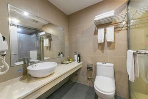 Un baño moderno con un espejo grande, un lavabo blanco, un inodoro y un box de ducha de vidrio.