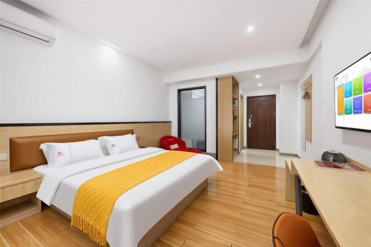 A hotel room with a bed, bedside table, a desk, and a chair.