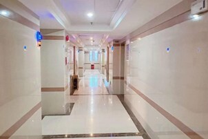 Un pasillo de hotel con un pasillo central, paredes con paneles decorativos e iluminación empotrada en el techo.