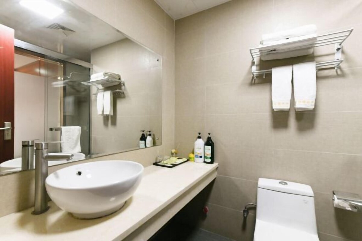 A modern bathroom with a large sink, mirror, and towel rack.
