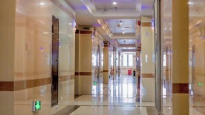 Un corridoio ampio e luminoso, con pavimento lucido, colonne imponenti e indicazioni per l'uscita di sicurezza.
