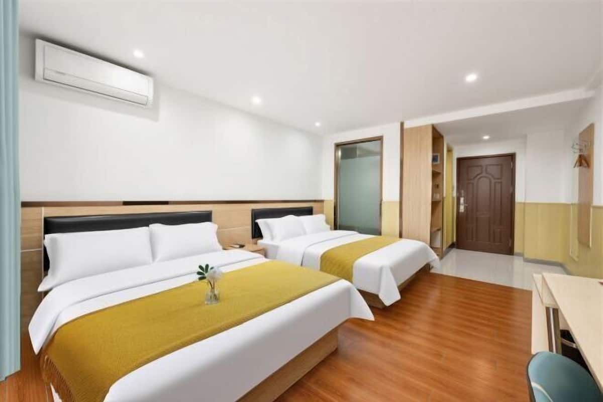 A hotel room with two beds, a desk, a chair, a wardrobe, and a door.