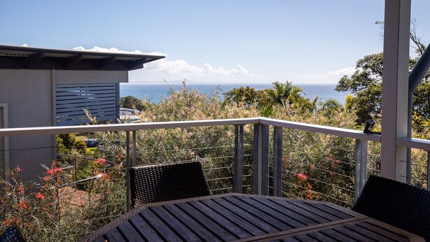 A balcony with a view of the ocean, a table, and chairs. - 3 Buoys - Set high with sweeping ocean views to Moreton Island and Cylinder Beach. (Point Lookout)