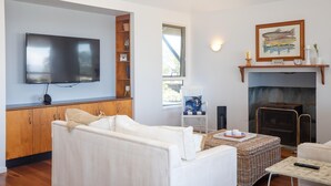 A modern living room with a flat-screen TV, a fireplace, and a cozy seating area. - 3 Buoys - Set high with sweeping ocean views to Moreton Island and Cylinder Beach. (Point Lookout)