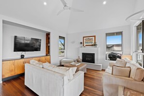 A modern living room with a flat-screen TV, a fireplace, and a sofa.