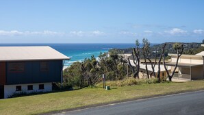 A coastal property with a view of the ocean, featuring a blue building and a yellow building with a balcony. - 3 Buoys - Set high with sweeping ocean views to Moreton Island and Cylinder Beach. (Point Lookout)