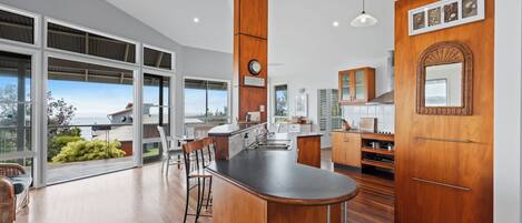 A modern kitchen with a large island, wooden cabinetry, and a view of the outdoors.