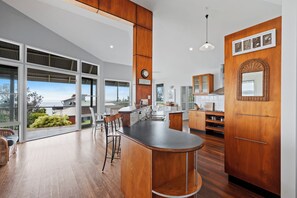 A modern kitchen with a large island, wooden cabinetry, and a view of the outdoors.