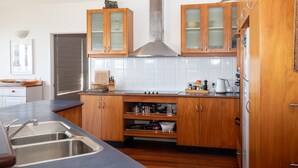 A modern kitchen with wooden cabinets, a stainless steel range hood, and a tiled backsplash. - 3 Buoys - Set high with sweeping ocean views to Moreton Island and Cylinder Beach. (Point Lookout)