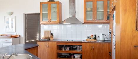 A modern kitchen with wooden cabinets, a stainless steel range hood, and a tiled backsplash.