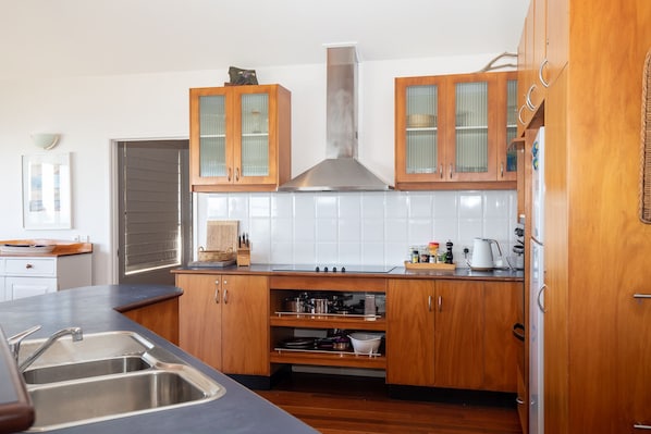 Une cuisine moderne avec des meubles en bois, une hotte de cuisinière en acier inoxydable et un dosseret carrelé.