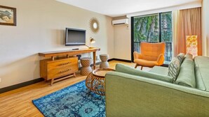 Un salon moderne comprenant un canapé, un téléviseur, un meuble en bois et une grande fenêtre donnant sur un paysage verdoyant.