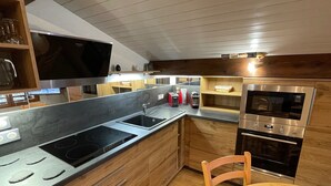 A modern kitchen with a central island, built-in oven, and microwave. - Attic Apartment 3 Rooms 74m², South Balcony, Private Parking, Wifi (La Clusaz)