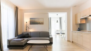 Una sala de estar moderna con un sofá gris, una mesita blanca y un cuadro en la pared.