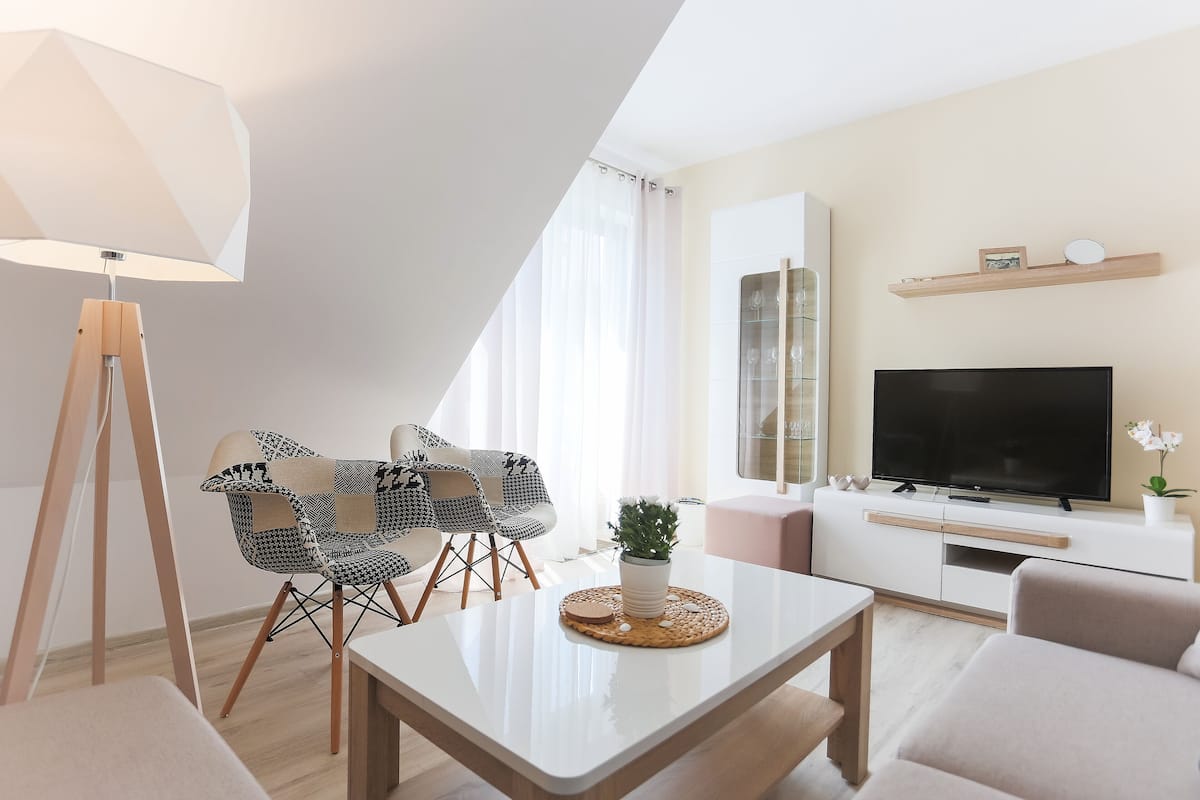 Een moderne woonkamer met een televisie, bank en eethoek.