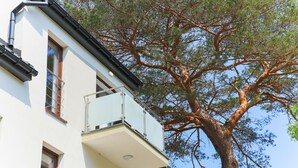 Un edificio moderno con un balcón y un gran árbol en primer plano.