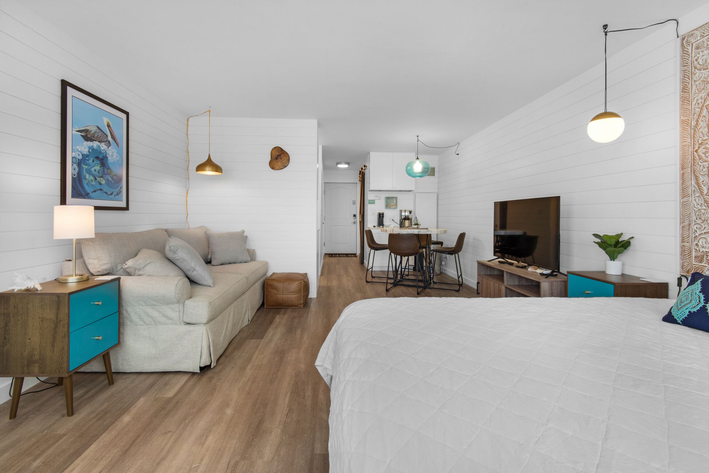 A modern hotel room with a large bed, a desk, a dining area, and a TV.