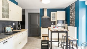 A compact kitchen with white cabinetry, a built-in oven, and a microwave. - Charming family house with terrace in Normandy (Beslon)