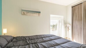 A bedroom with a bed, a painting, a bedside table with a lamp, and a window with curtains. - Charming family house with terrace in Normandy (Beslon)