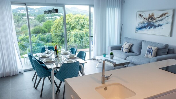 Eine moderne Küche mit einer großen Kochinsel, einem Essbereich mit blauen Stühlen und einem Sofa.