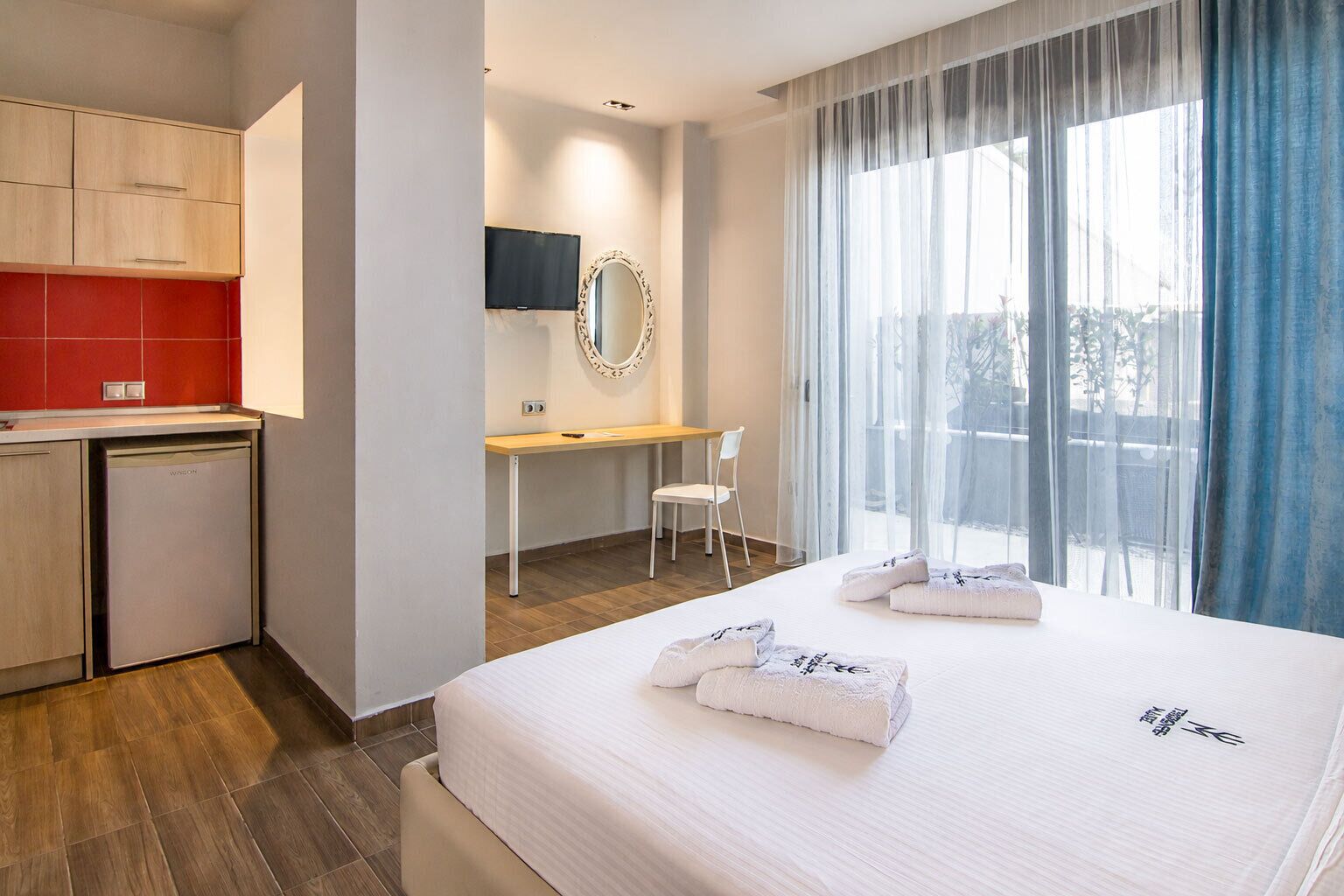 Una habitació d'hotel amb llit, escriptori, cadira, televisió i vistes a l'exterior.