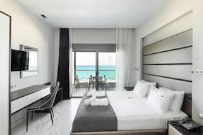A modern hotel room with a bed, a desk, a chair, a TV, and a balcony with a view of the sea. - Tridente Mare (Kassandra)