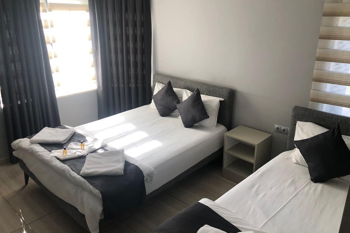 A hotel room with a bed, bedside tables, and a window with curtains.