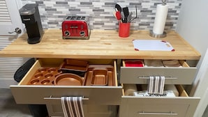 Een keuken met een broodrooster, een rode mok en een keukendoekhouder op het aanrecht.