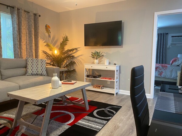A modern living room with a sofa, a coffee table, a TV, and a bookshelf.
