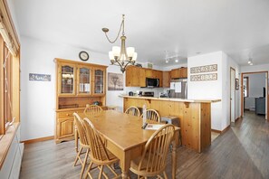 Une cuisine spacieuse dotée de meubles en bois, d’un îlot central et d’un coin repas avec des chaises en bois.