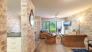 Une cuisine spacieuse avec un coin repas, caractérisée par des murs en briques, un plancher en bois et des meubles en osier.
