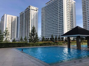 A swimming pool with a pavilion, surrounded by tall residential buildings and greenery. - Affordable Place to Stay in Tagaytay (Tagaytay)