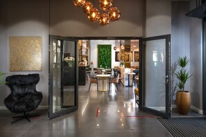 Un intérieur moderne avec une entrée dotée d’une porte en verre, une chaise noire, une table ronde et une plante verte.